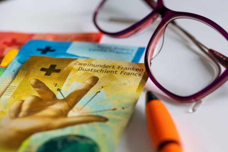 francs suisses et lunettes posées sur une table